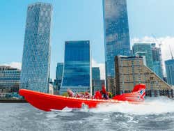 An orange inflatable speed boat tears through the water carrying passengers