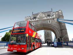 A red double decker tourist bus drives on a bridge in London