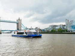 A boat sails the River Thames, the London Bridge behind