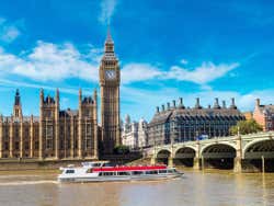 A cruise boat passes under a bridge, Big Ben behind